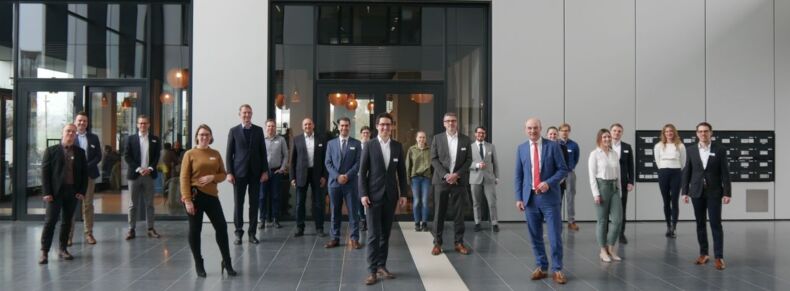 The picture shows participants of the kick-off workshop for the consortium benchmarking "Circular Economy - Lifecycle Management in Manufacturing Companies". Twenty people stand at a distance from each other in an entrance hall.